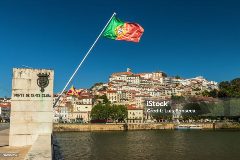 With the Portuguese flag on the foreground and a blue sky.